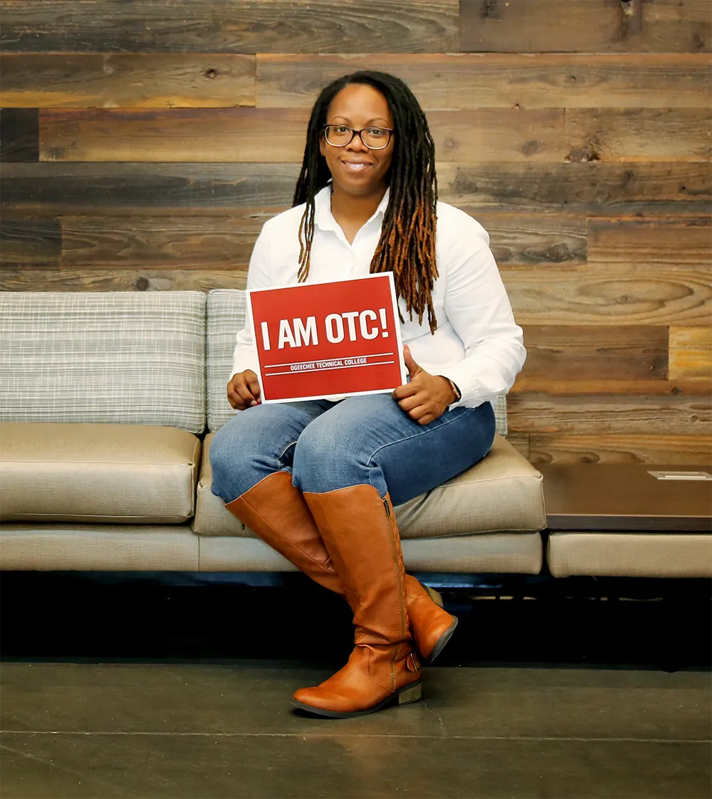 OTC Student in chair with sign